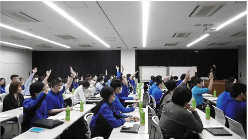 広い部屋で参加者が手を挙げ、積極的に参加している様子
